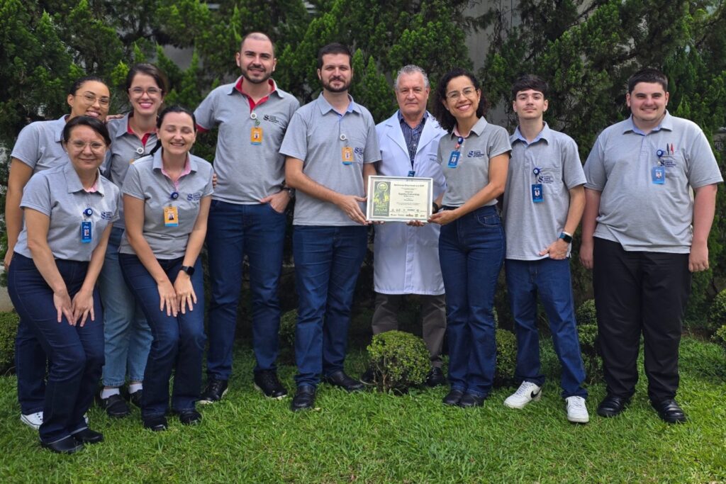 Equipe multidisciplinar do SESMT do HSC Blumenau segurando certificado de melhor empresa de Segurança e Saúde no Trabalho, na categoria Hospitalar.