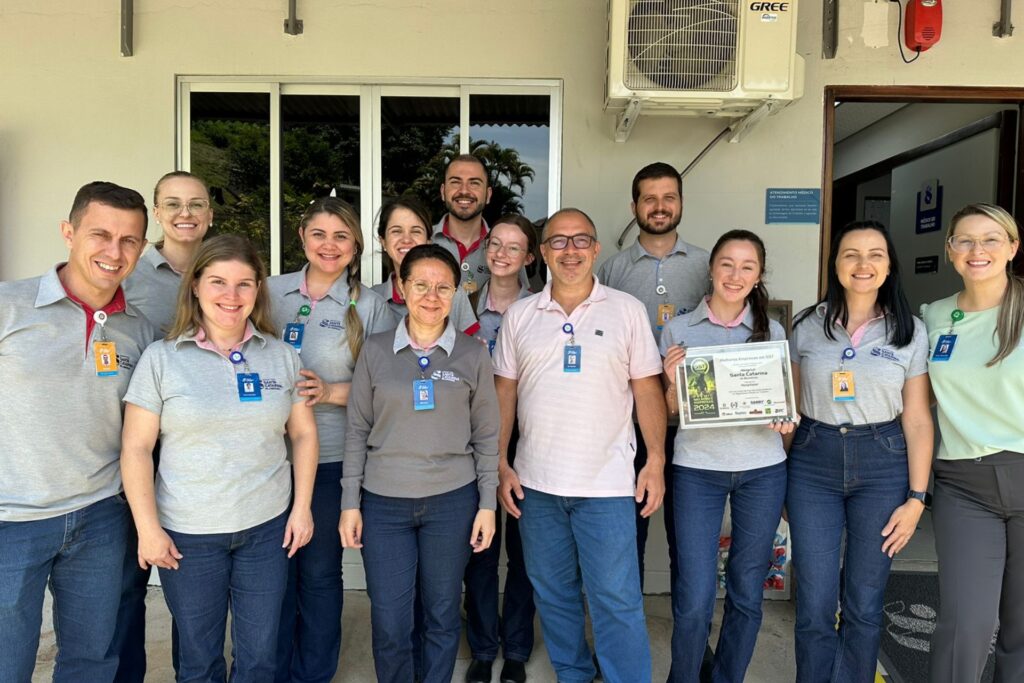 Equipe multidisciplinar do SESMT do HSC Blumenau segurando certificado de melhor empresa de Segurança e Saúde no Trabalho, na categoria Hospitalar